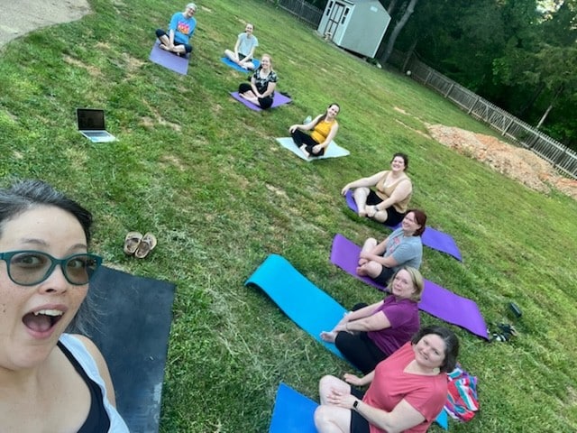 The group doing yoga outside in the park.